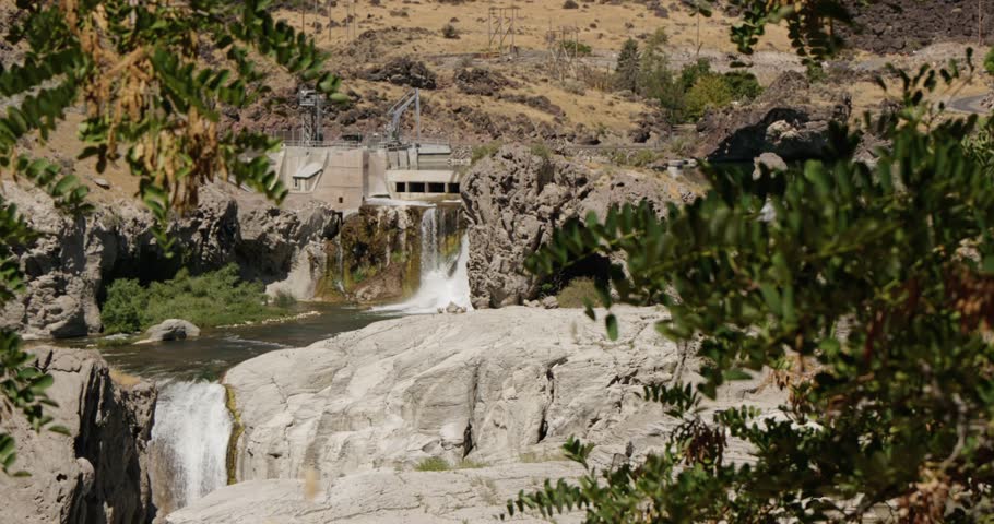 A view of Shoshone Falls plunging into the Snake River gorge, surrounded by rocky terrain and dry hills in Twin Falls, Idaho