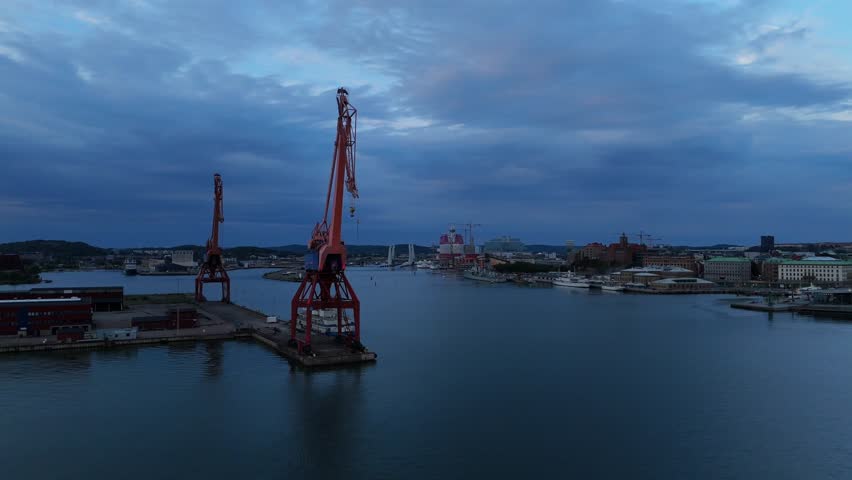 Aerial view of large red cranes at the harbor with city buildings in the background in Gothenburg, Vastra Gotaland Count, Sweden.