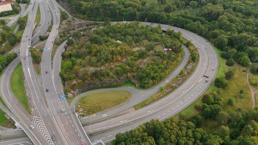 Aerial view of highway interchange surrounded by lush green forest and rocky terrain in Gothenburg, Vastra Gotaland County, Sweden.