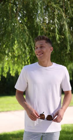 Young man wearing white t-shirt and sunglasses outdoors