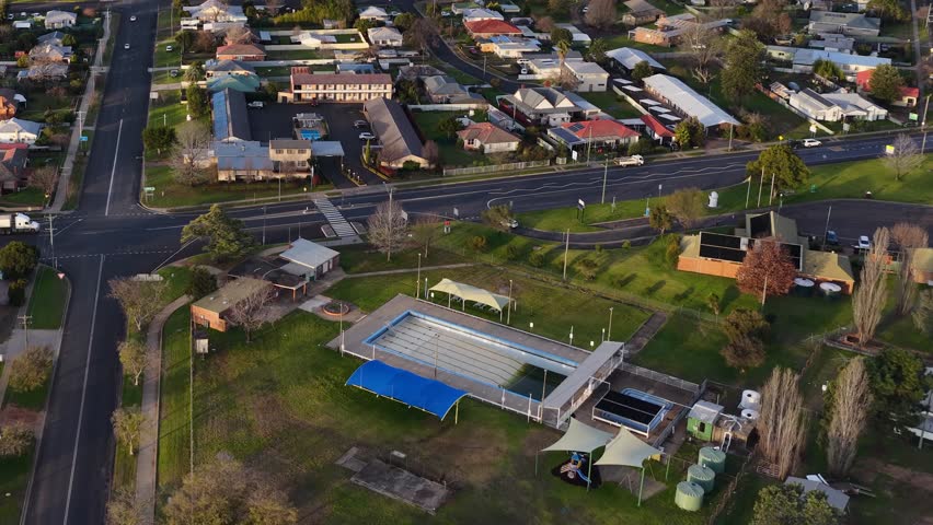 High-angle drone shot of a suburban township with houses and a swimming pool in Australia.