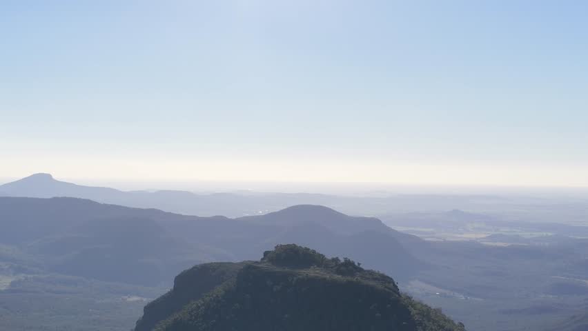 Wide aerial shot of rugged mountain peaks and hazy horizon in Warrumbungle National Park, Australia.
