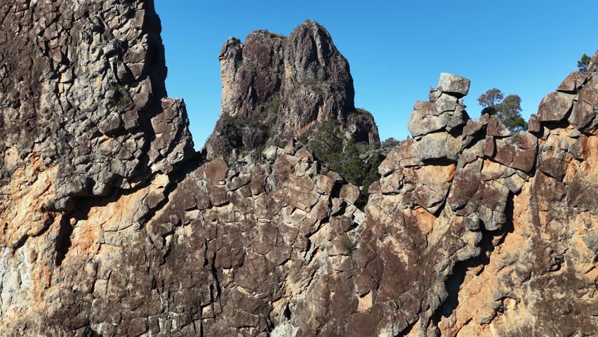 Wide shot of jagged volcanic peaks under clear blue sky in Warrumbungle National Park, Australia.