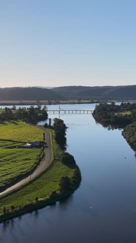 High-angle drone shot of the Clarence River winding through green farmland in Maclean, Australia.