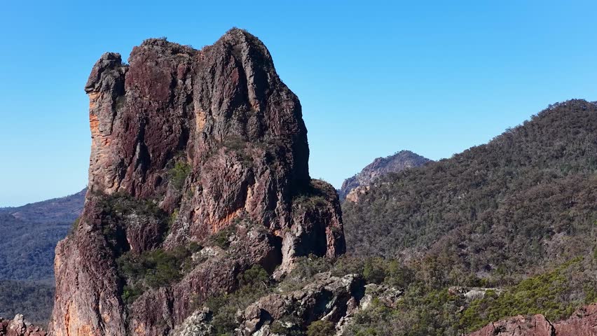 Wide shot of craggy volcanic peaks under clear blue sky in Warrumbungle National Park.
