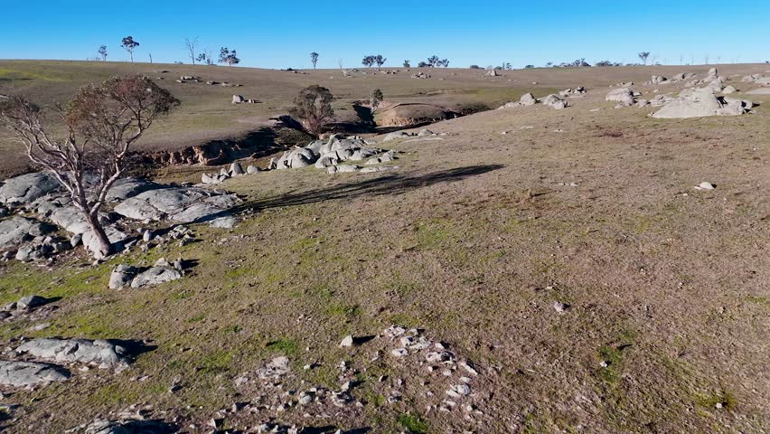 Drone flight over rocky terrain and dry grass fields in Uralla, New South Wales, Australia.