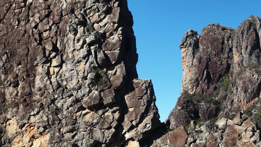 Panning shot of ancient volcanic peaks under clear blue sky in Warrumbungle National Park.