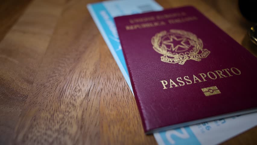 An Italian passport with biometric symbol on top of a boarding pass, representing official travel and identification documents.