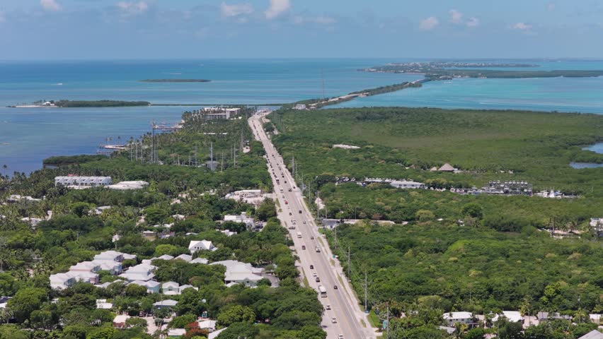Aerial view of the Overseas Highway stretching through the lush tropical landscape and turquoise waters of Islamorada, Florida, United States.