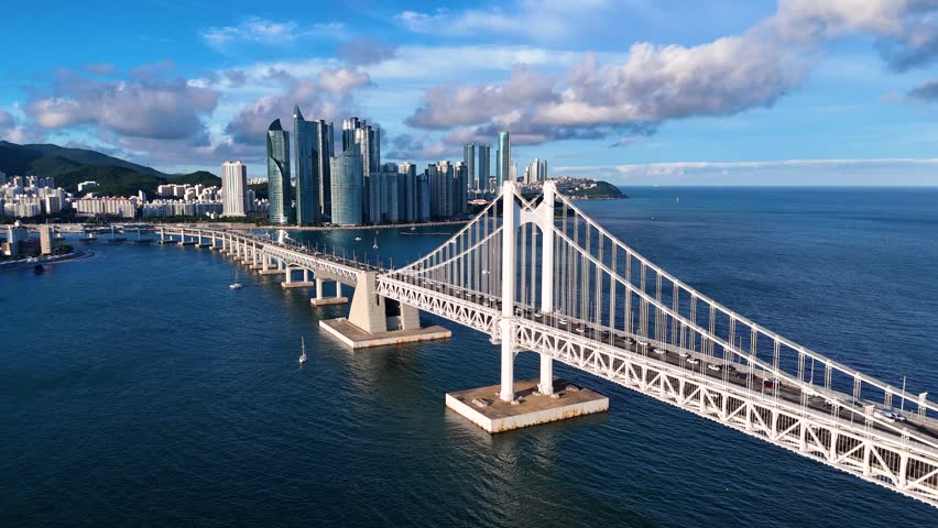 Aerial view of Gwangan Bridge spanning the bay with the modern skyline and coastal cityscape in the background in Busan, Busan, South Korea.