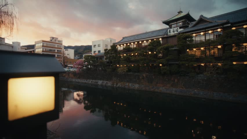 Wide dusk shot of the Tōkaikan historic ryokan reflected in the Matsukawa River, Ito, Shizuoka, Japan.