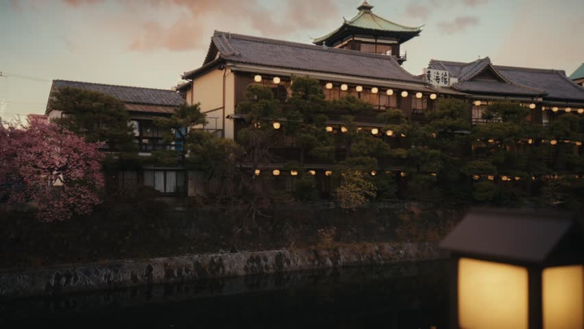 Wide dusk shot of the Tōkaikan historic ryokan reflected in the Matsukawa River, Ito, Shizuoka, Japan.