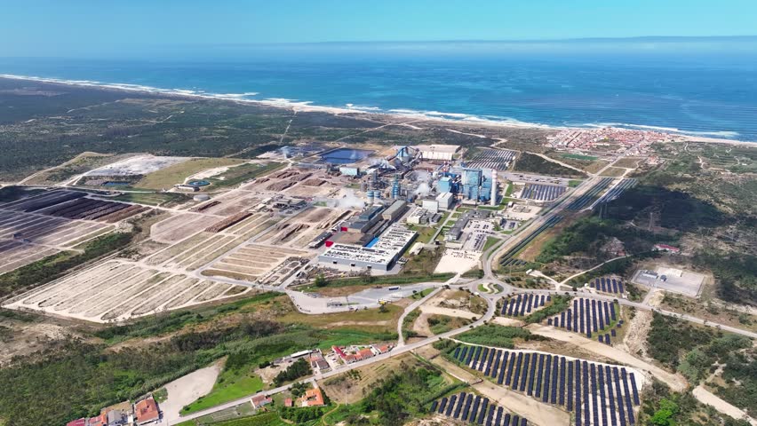 Aerial view of an industrial pulp and paper mill, including wood processing facilities and a solar farm, located on the Atlantic coast