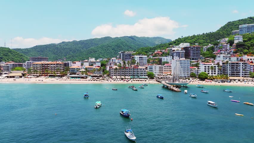 Aerial view of Los Muertos Beach Pier with boats on the water and the coastal city skyline in Puerto Vallarta, Jalisco, Mexico.