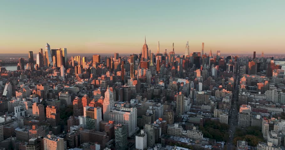 Aerial view of Manhattan skyscrapers at sunset with warm light hitting the buildings in New York, New York, United States.