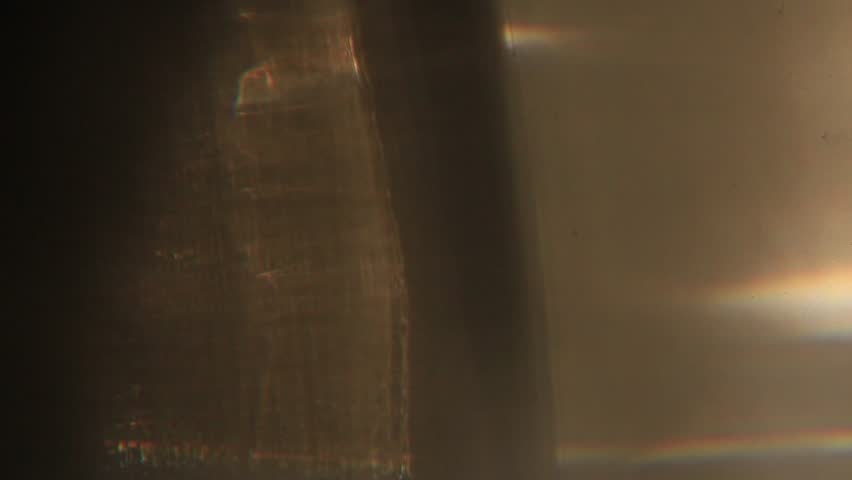 A series of macrovideo demonstrating the physics of light in an uneven black glass with scratches, water stains, and fingerprints, showing the refraction of light in glass and water droplets, chromatic aberration and dispersion, and lens flare.