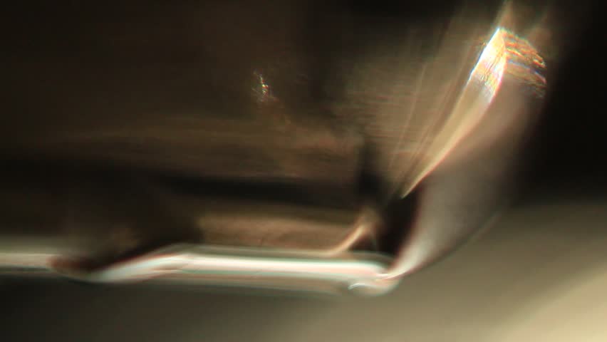 A series of macrovideo demonstrating the physics of light in an uneven black glass with scratches, water stains, and fingerprints, showing the refraction of light in glass and water droplets, chromatic aberration and dispersion, and lens flare.
