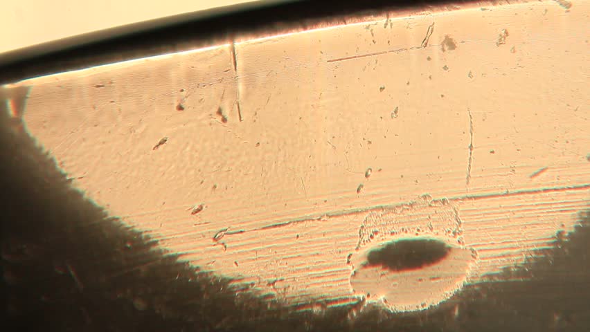 A series of macrovideo demonstrating the physics of light in an uneven black glass with scratches, water stains, and fingerprints, showing the refraction of light in glass and water droplets, chromatic aberration and dispersion, and lens flare.