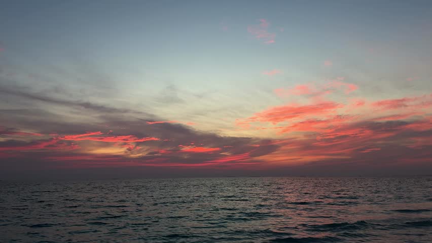 Ocean waves under colorful sunset sky with pink clouds over Maldives horizon. Concept of nature, travel, relaxation, seascape, tropical destination, peaceful atmosphere.
