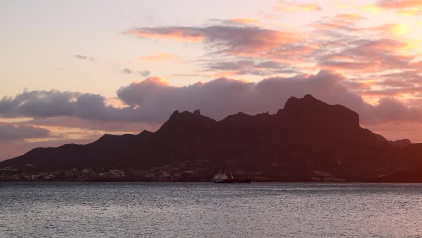 Fiery Skies at Dusk As Ship Passes Beneath Silhouetted Mountain at Sunset in Cape Verde