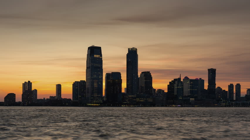 Jersey City skyline timelapse from sunset to twilight with Exchange Place skyscrapers and Hudson River waterfront. New Jersey, USA