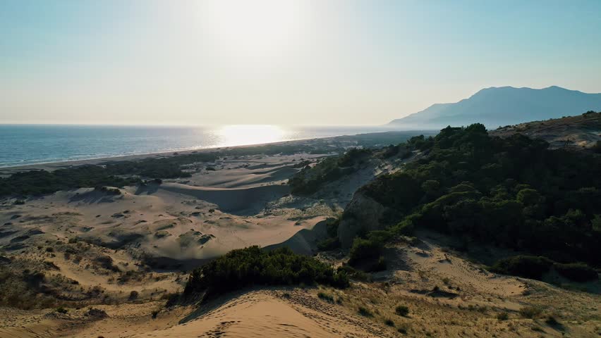 Patara sand dunes sunset aerial view capturing the dramatic golden hour light over the vast desert-like landscape in Antalya, Turkey. Majestic drone shot of coastal dunes.