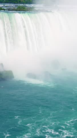 Boat near thunderous waterfall with birds, aerial photographer capturing spray and turquoise currents, rapid whitewater and cliff ledge visible, raw power and spray filling scene, dramatic motion
