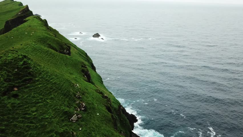 Ocean and green hills, Faroe Islands. Natural landmark of Mykines Island.