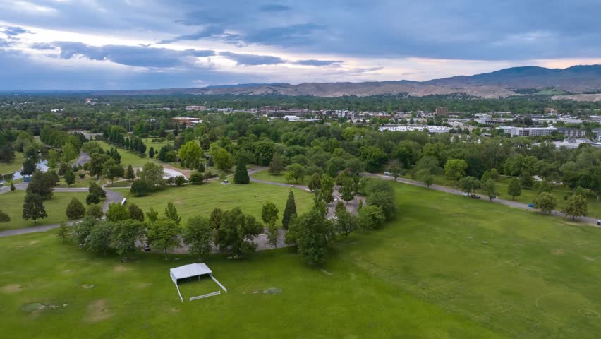 Aerial view of Ann Morrison Park featuring lush green lawns, mature trees, and winding paths under a cloudy sky in Boise, Idaho, United States.