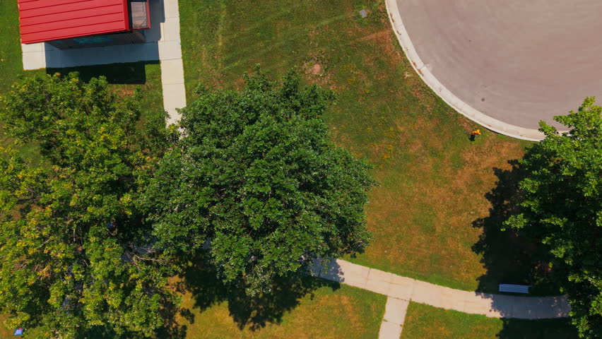 Aerial topdown rising shot of suburban park featuring a children