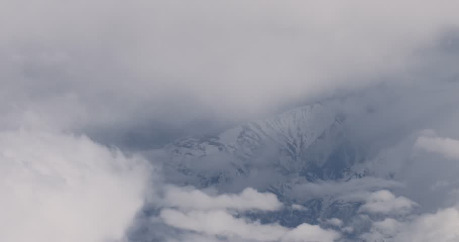 Flying view above clouds and mountains.