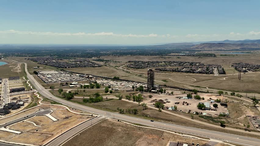 Aerial view of the historic Leyden mine tower surrounded by suburban development, open fields, and winding roads in Jefferson County, Colorado, United States.