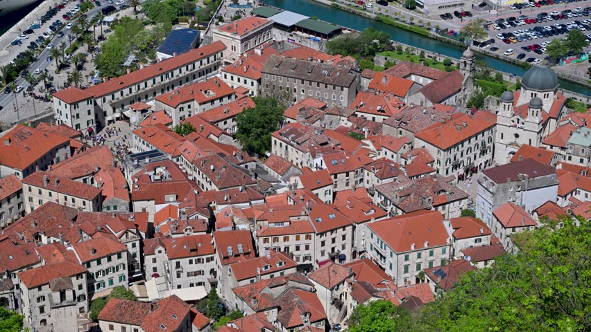 Aerial view zooming into the historic old town of Kotor, Montenegro. The medieval city features stone buildings with distinctive red tiled roofs