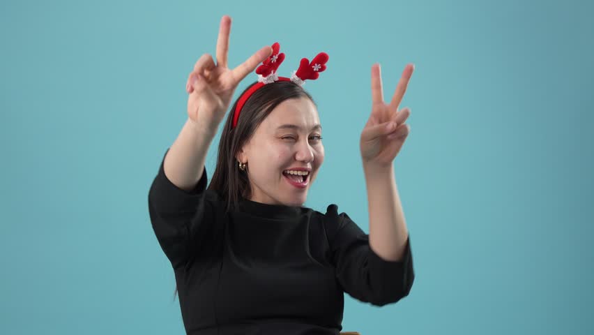 Cheerful young woman dancing with Christmas antler headband