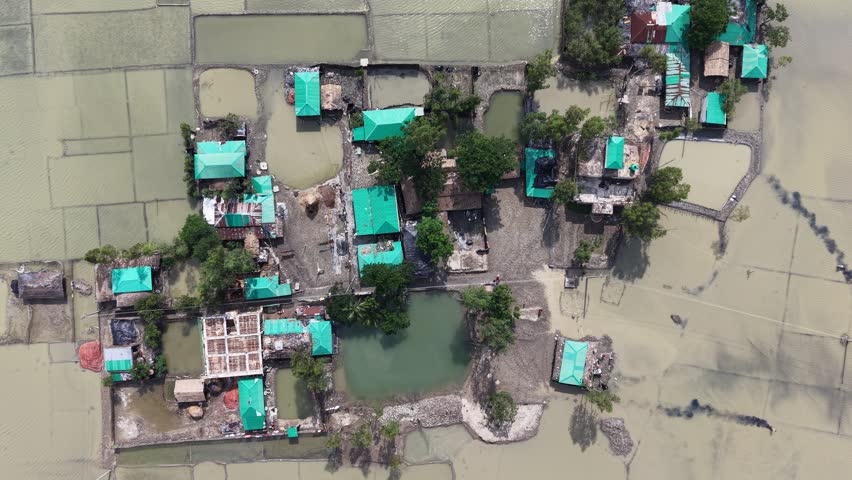 Aerial view of flooded residential area with green-roofed houses surrounded by water in Banshkhali Upazila, Chittagong Division, Bangladesh.