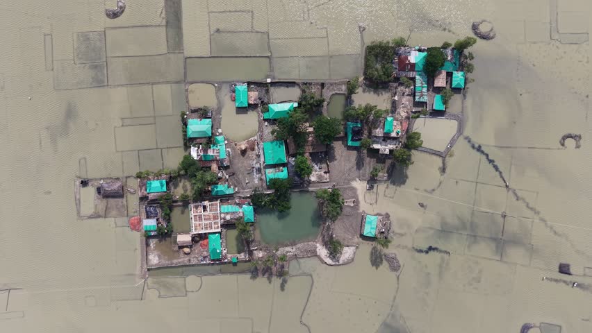 Aerial view of a small settlement with green-roofed houses surrounded by flooded fields and ponds in Banshkhali Upazila, Chittagong Division, Bangladesh.