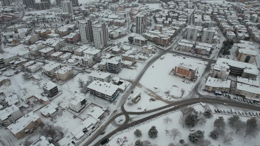 Aerial view of Karaman Fortress surrounded by snow-covered city streets and residential buildings in winter in Karaman Merkez, Karaman, Turkiye.