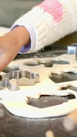 Vertical video: Pressing cutter into dough apron hands lifting cuts placing cookies on pan to bake. Pastry, shapes, tray, star, flour, measuring, vertical video