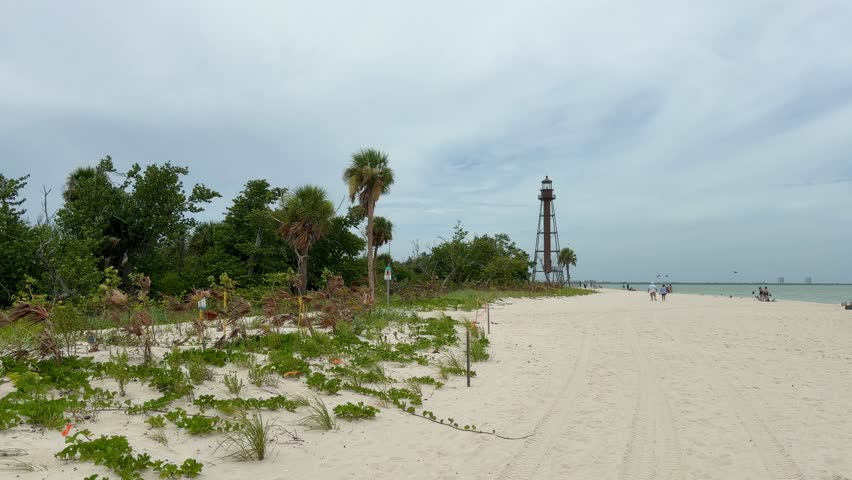 Sanibel Beach, USA - July 18, 2026: Wide sandy beach on Sanibel Island with palm trees, dramatic cloudy sky and calm Gulf of Mexico, creating a peaceful tropical summer destination with copy space.