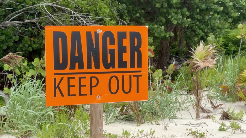 Orange "Danger Keep Out" warning sign at Sanibel Lighthouse Beach, Florida. The sign marks a restricted area near the shoreline, emphasizing public safety in a popular coastal destination.