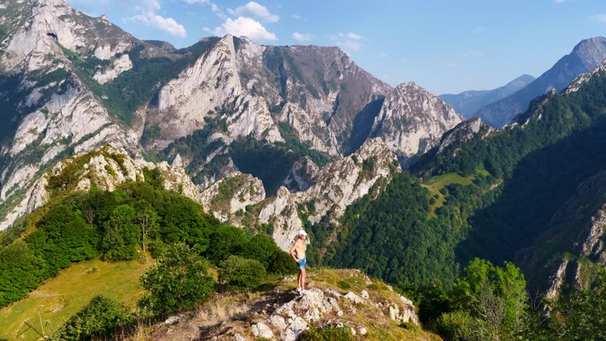 a hiker in Picos de Europa in Cantabria, Spain. Drone orbiting shot of a tourist standing on top of a mountain at sunset. Hiking and travel in Spain, Picos de Europa region. High quality 4k footage