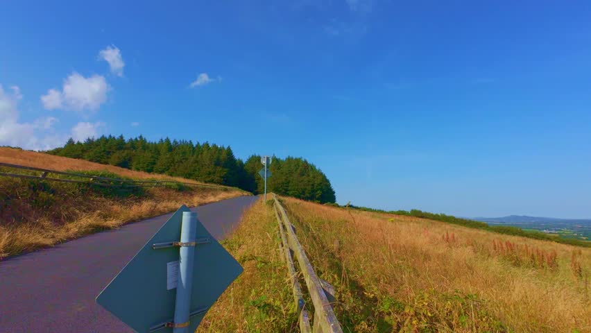 Grassy hill slope under blue sky with light clouds