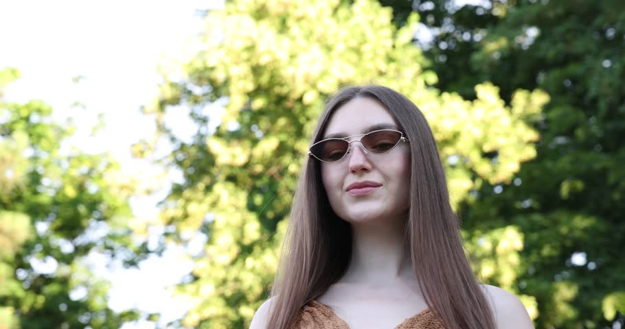 Beautiful young woman wearing stylish sunglasses outdoors, low angle view