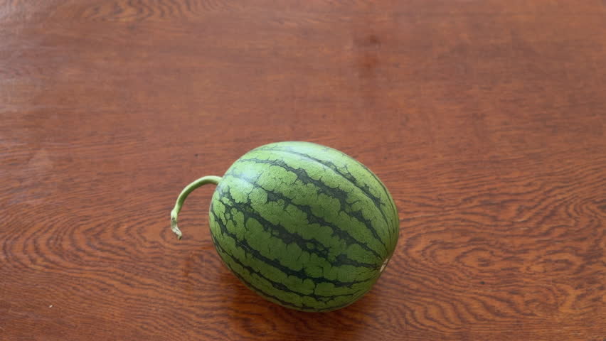 Round Watermelon Resting on a Wood-Grain Table
