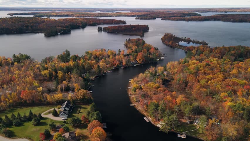 An aerial scene of a river bend framed by colorful autumn trees and scattered lakeside residences