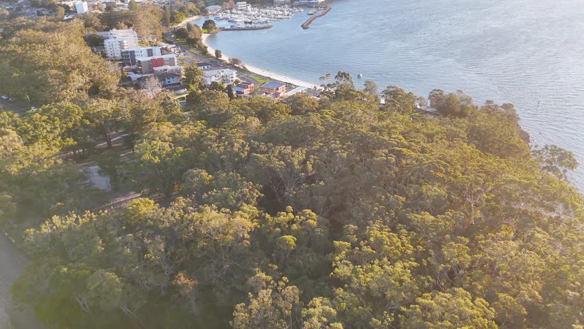 High-angle drone shot of Nelson Bay marina, beach, and coastal buildings in New South Wales.