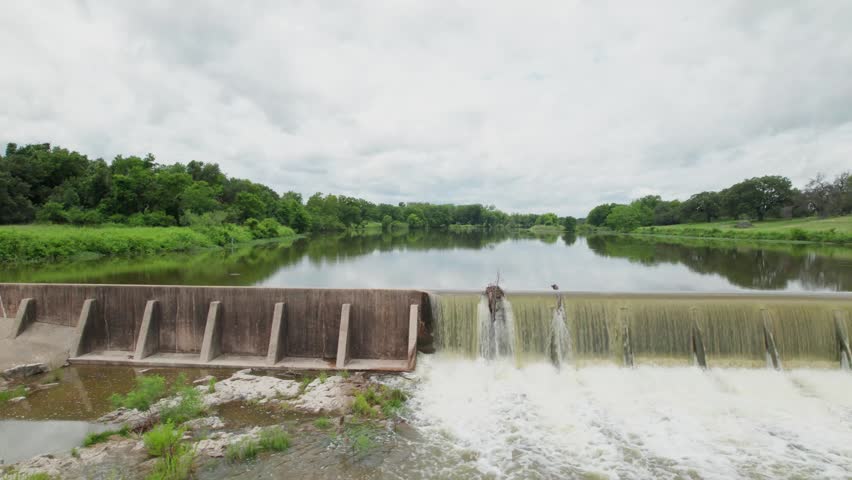 Aerial video of a dam on the Pedernales river, Texas. Camera is facing the dam and pans right.