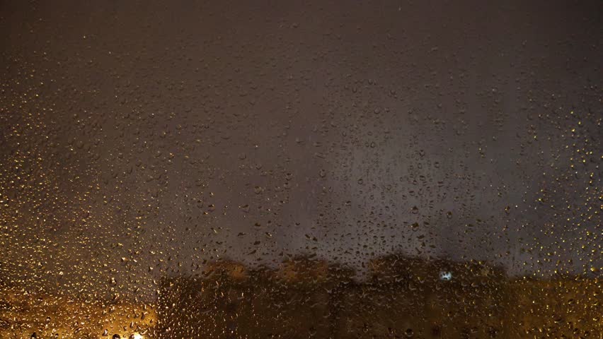 A time-lapse of nighttime rain and lightning seen through a wet window during a stormy sky over Lisbon Portugal