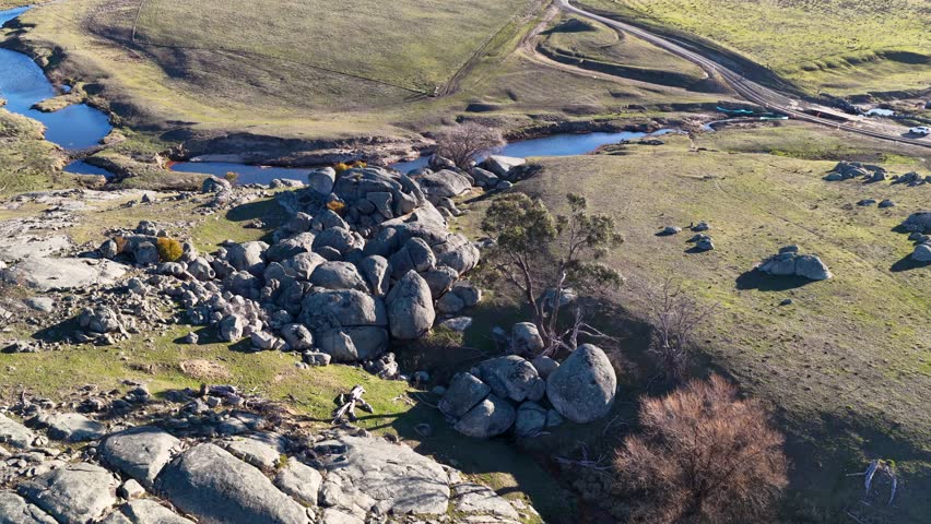 Drone shot of granite rock formations and a winding creek in rural New South Wales.