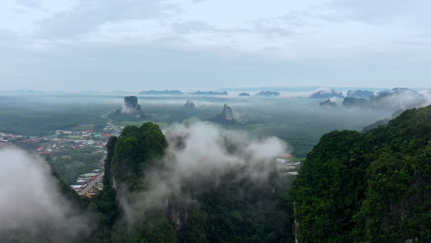 Expansive mountain vistas evoke tranquility and inspire sense of wonder. Lush green peaks fade into misty clouds, framing quaint town nestled below. This serene landscape captures beauty of nature and invites contemplation of peaceful rural life. feeling of calm and escape is perfectly represented within this expansive environment.